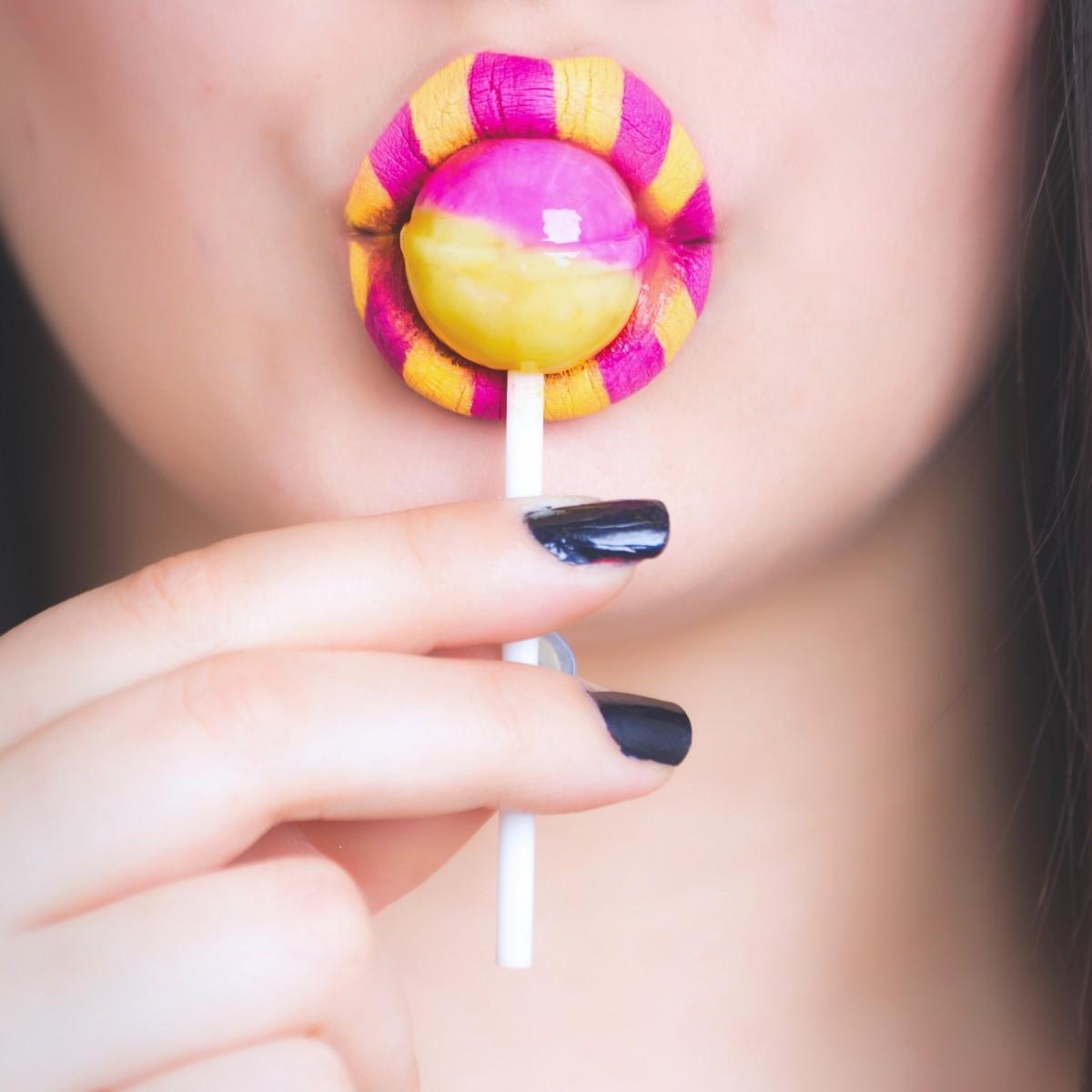 Woman Eating Pink and Yellow Lollipop